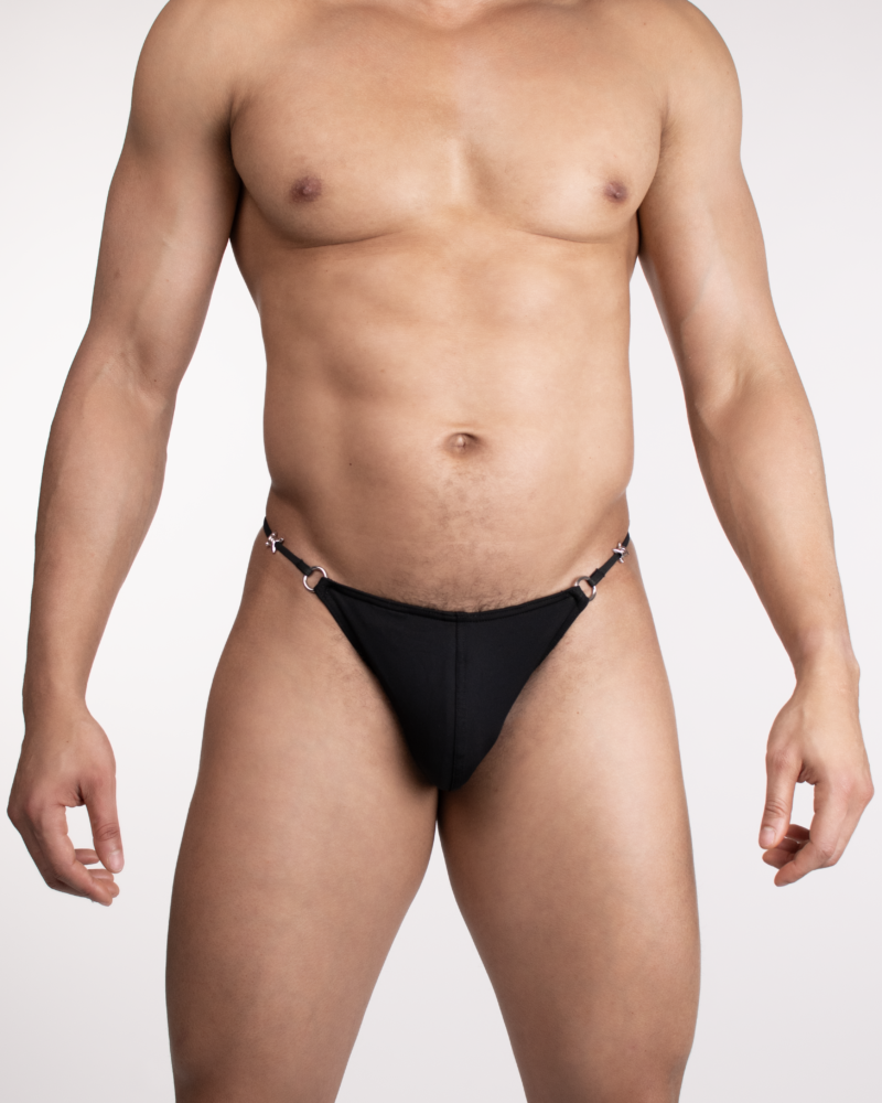 Front view of a man in black micro thong with metal rings